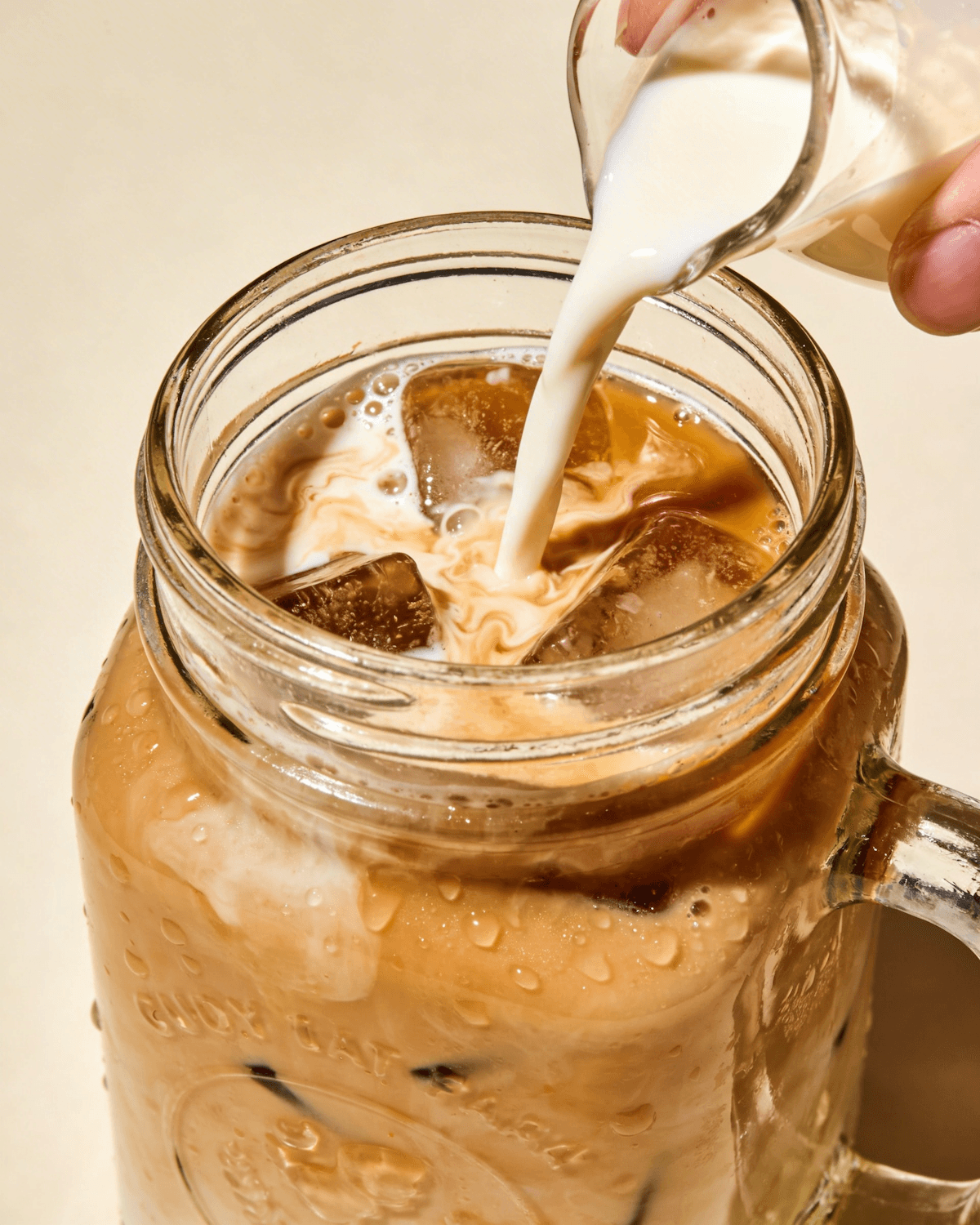 Leite sendo despejado em um copo de café gelado